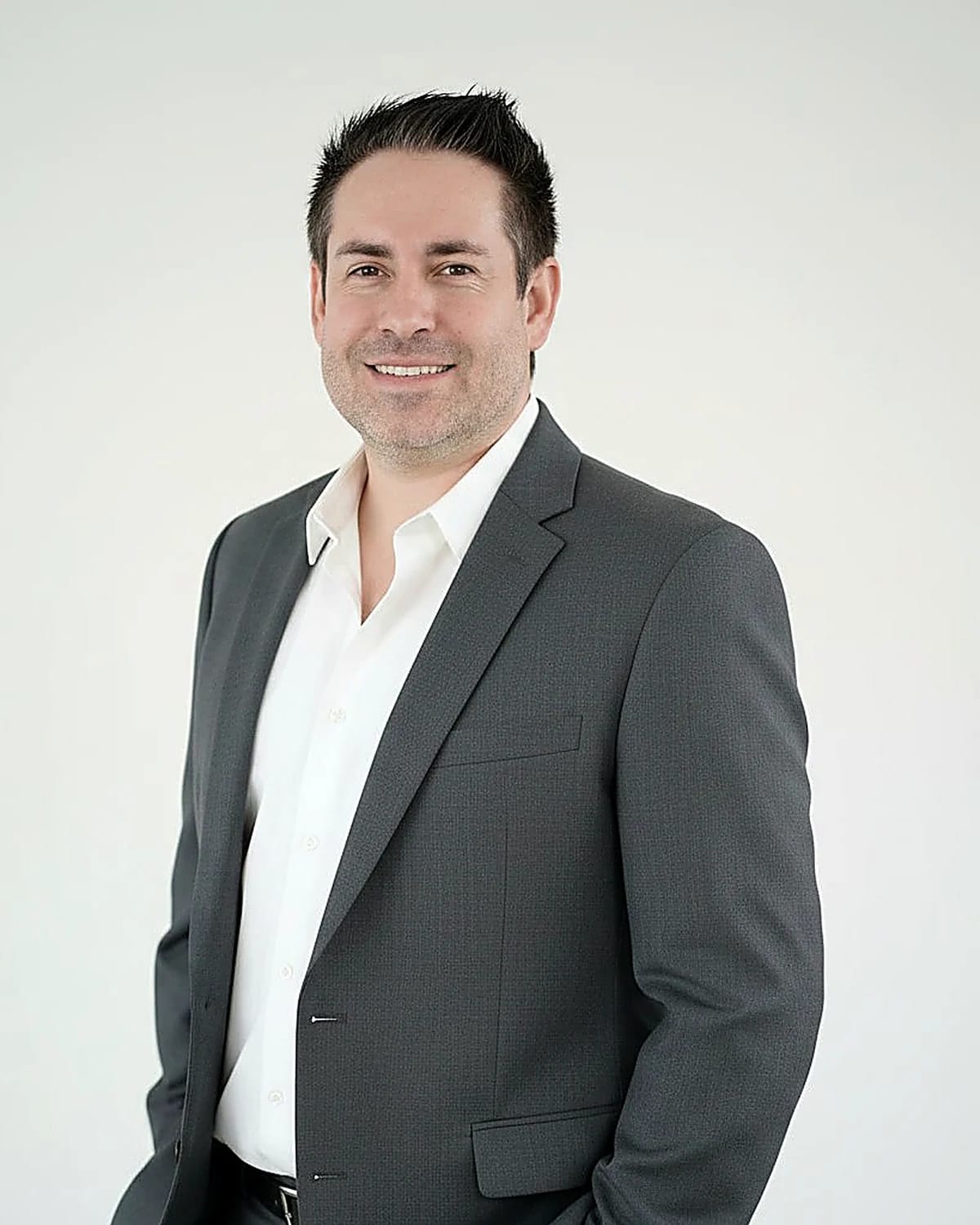 Portrait of Dr. Justin Schwarting, DNP, PMHNP-BC, smiling in a grey suit